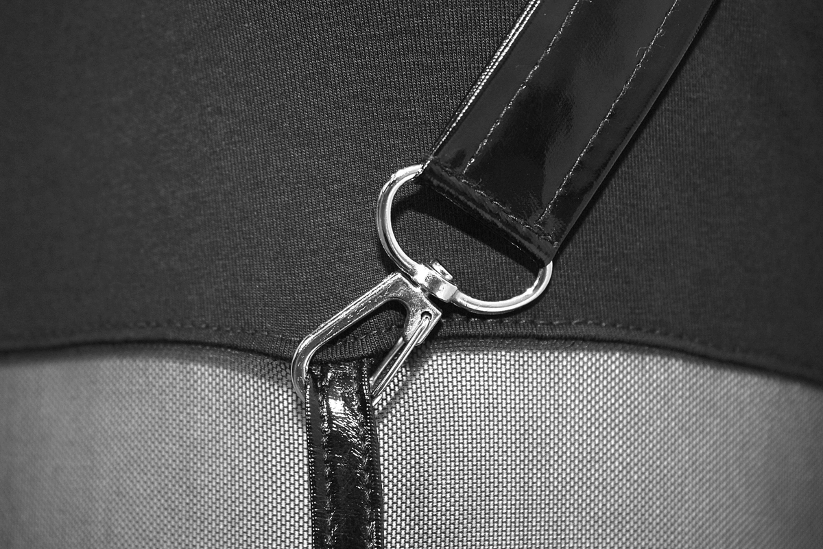 Close-up of a sleek black dress strap with shiny metal buckle, showcasing gothic punk style details.