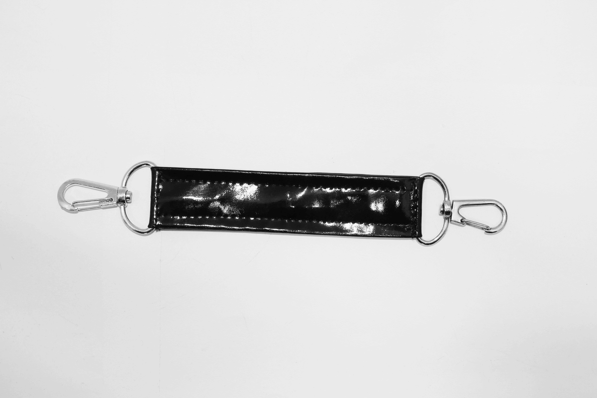 Black glossy strap with metal clips, perfect for attaching to bags or accessories in a stylish and edgy design.