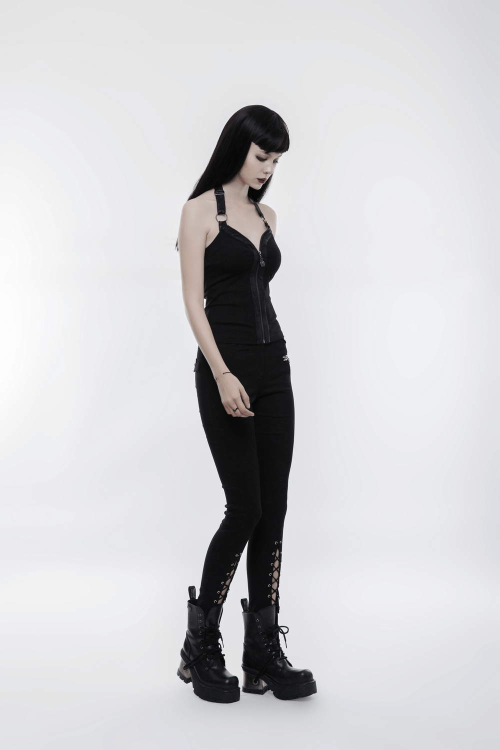 Edgy black zippered halter camisole with ring detailing, paired with stylish black pants and chunky boots.