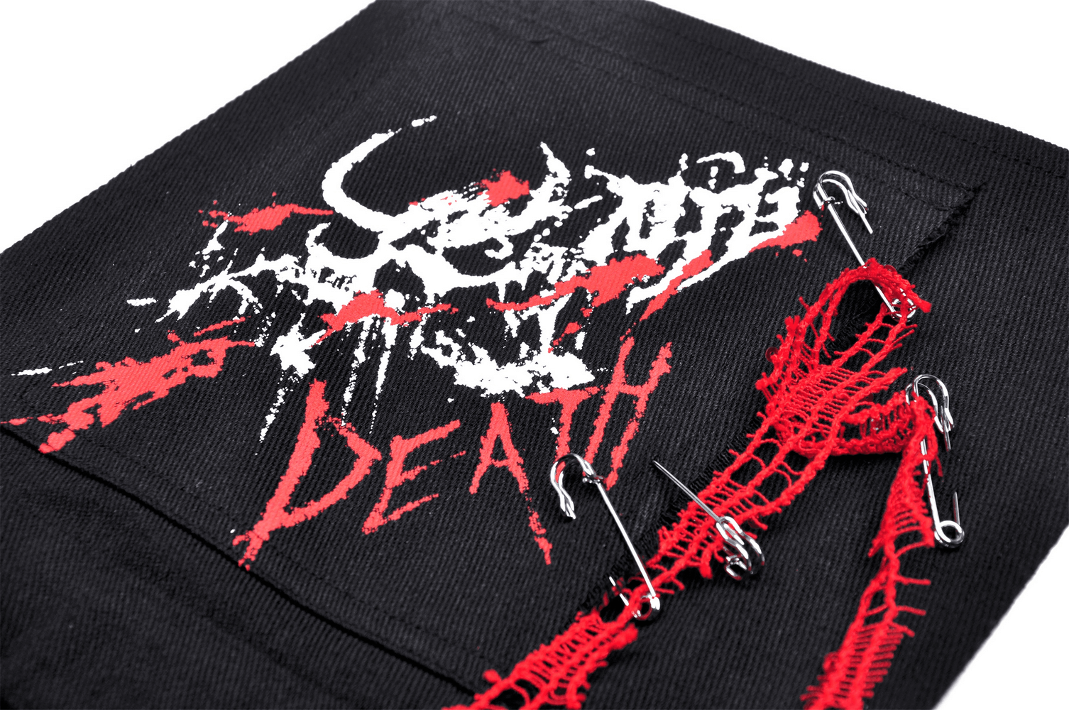 Close-up of a black fabric with red and white graphic design reading 'Death' and decorative safety pins.