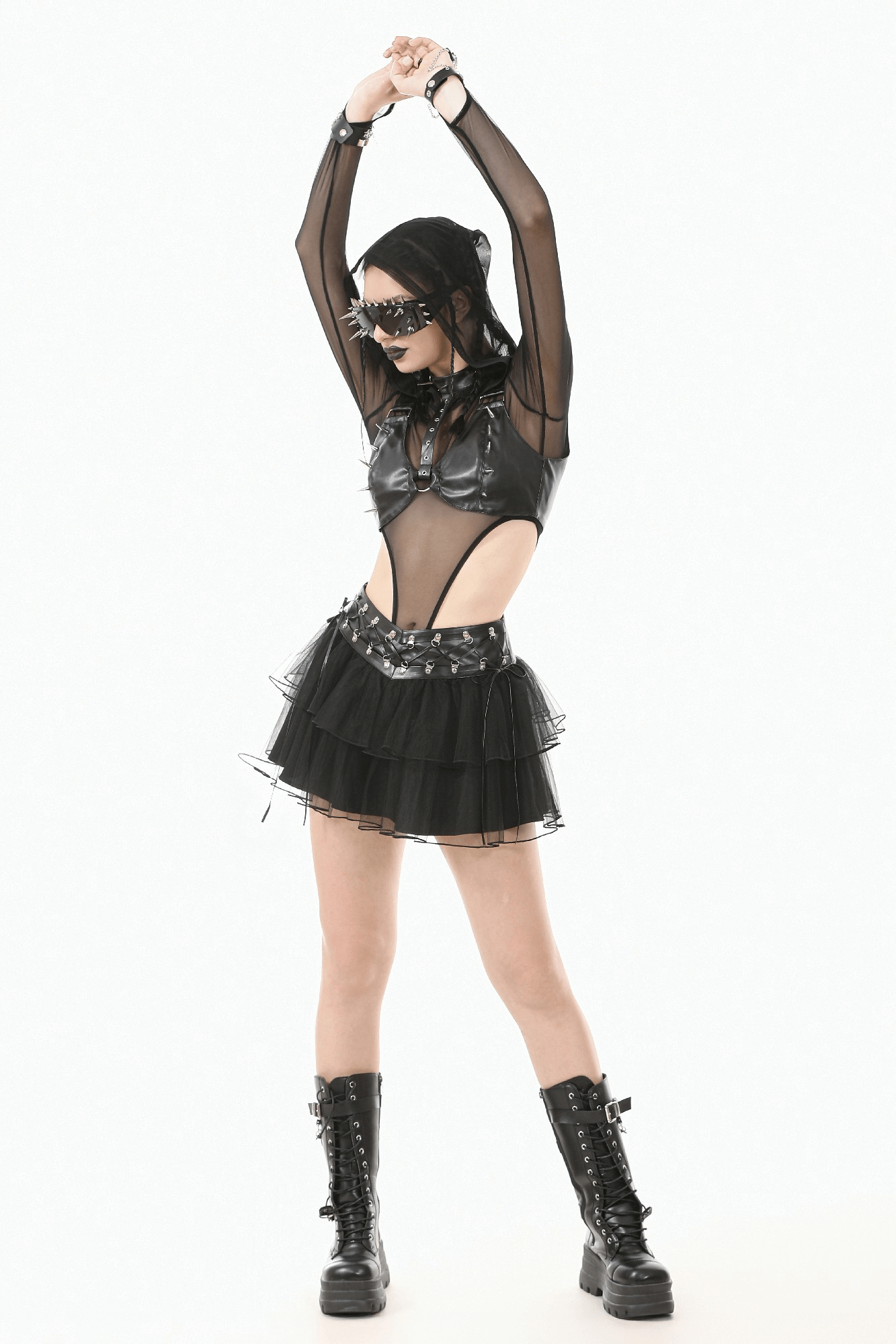 Gothic punk model in edgy faux leather top, layered skirt, and combat boots showcasing bold alternative fashion.
