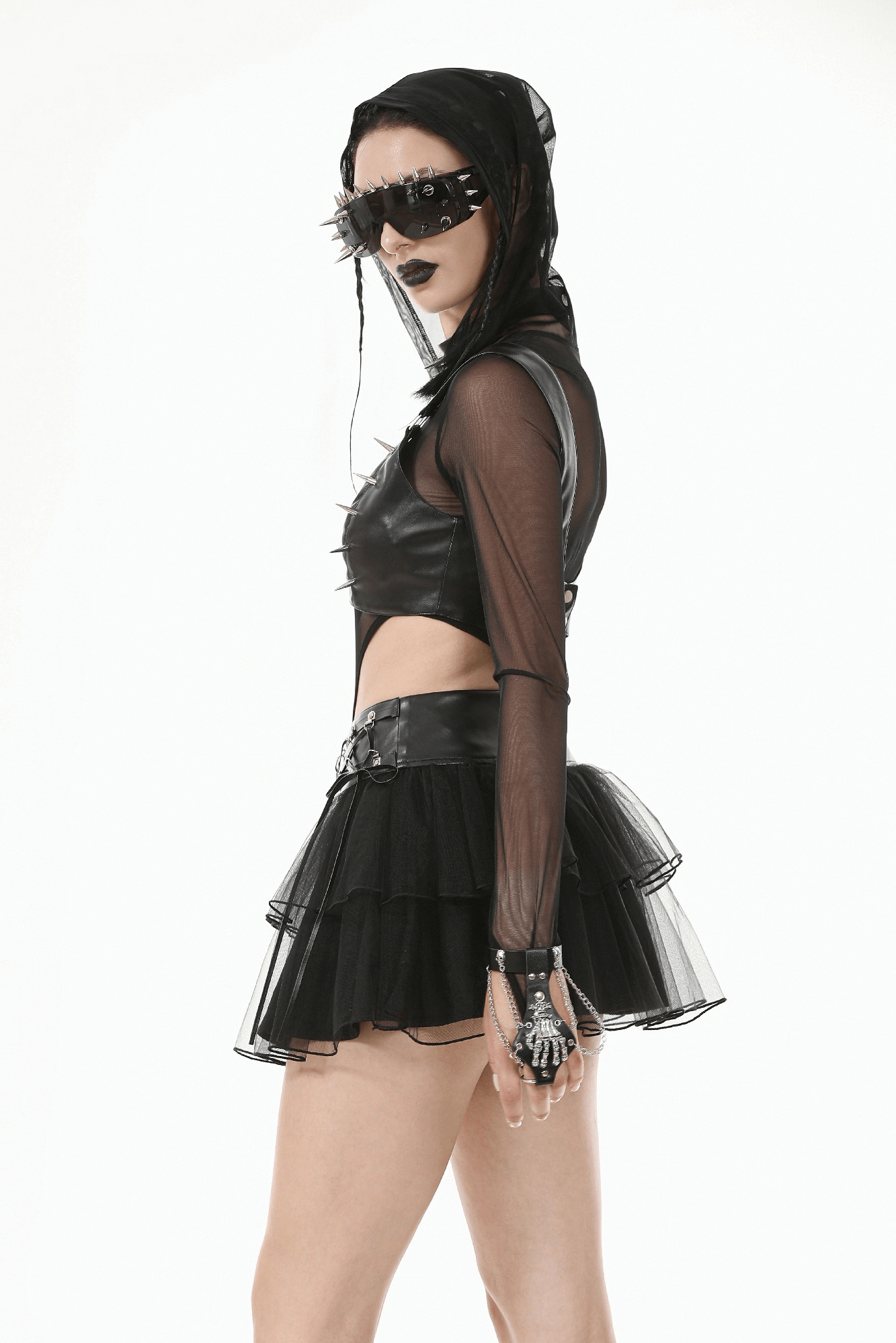 Model in edgy gothic outfit with faux leather top, tulle skirt, and spikes, showcasing bold punk style.
