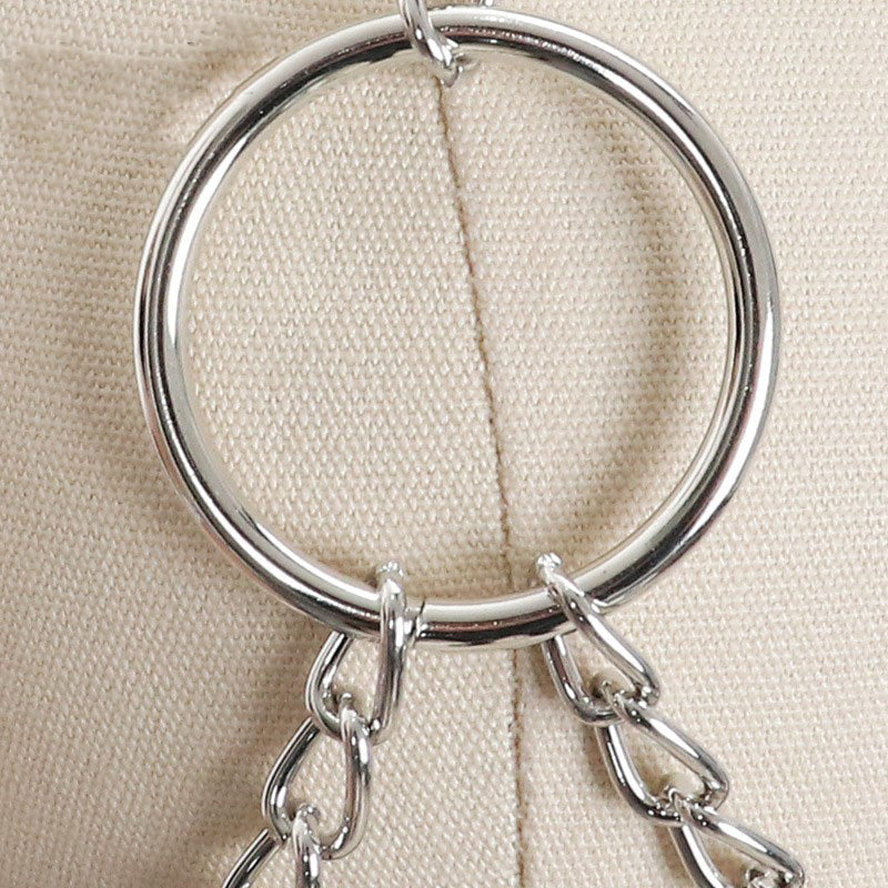 Close-up of a silver ring and chain detail on a faux leather breast bondage harness belt.