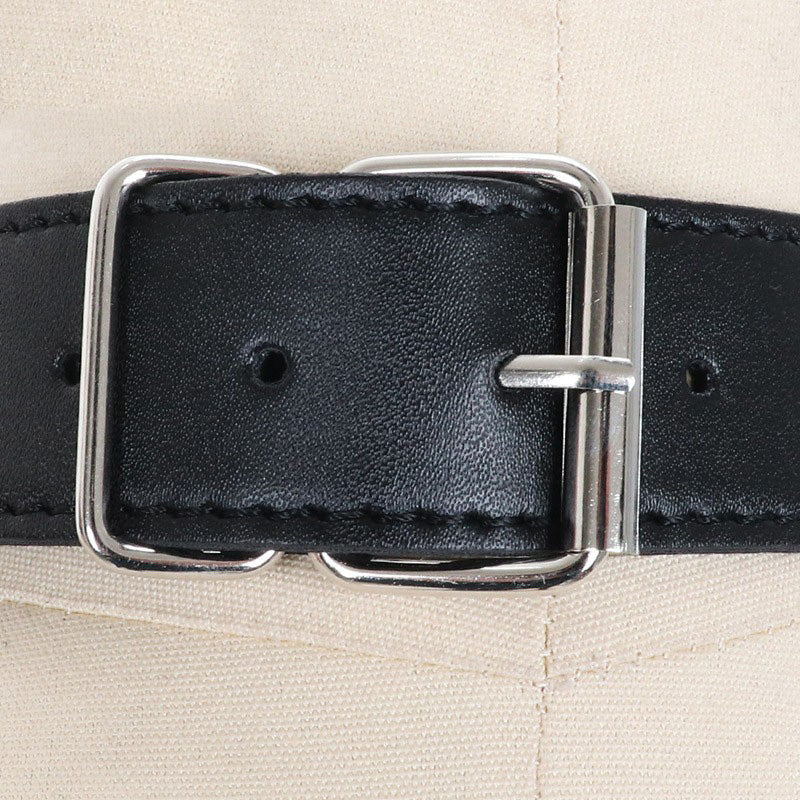 Close-up of black faux leather breast bondage belt buckle with silver details