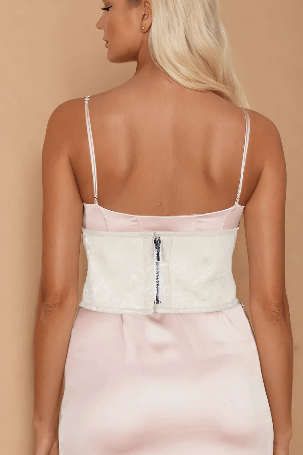 Back view of a woman in a corset belt with zipper, showcasing elegant lace design and stylish spaghetti straps.