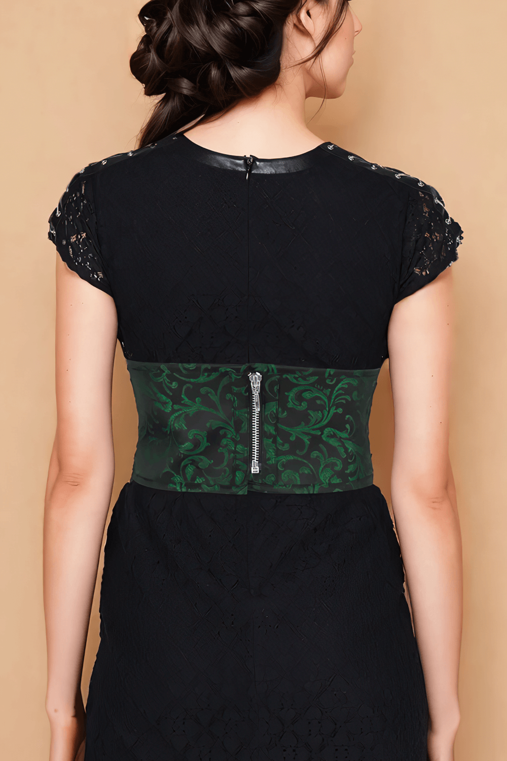 Back view of a model wearing a black dress featuring a green brocade corset belt with zip closure.