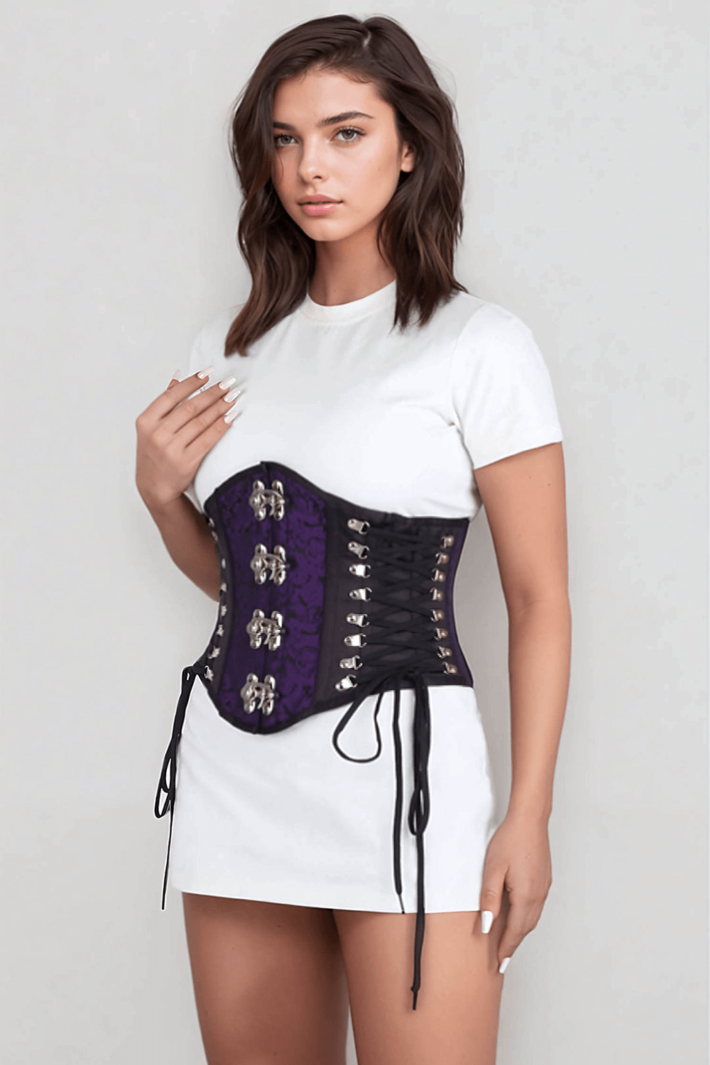 Model wearing a purple brocade corset with satin accents and tight lacing, showcasing its elegant design.