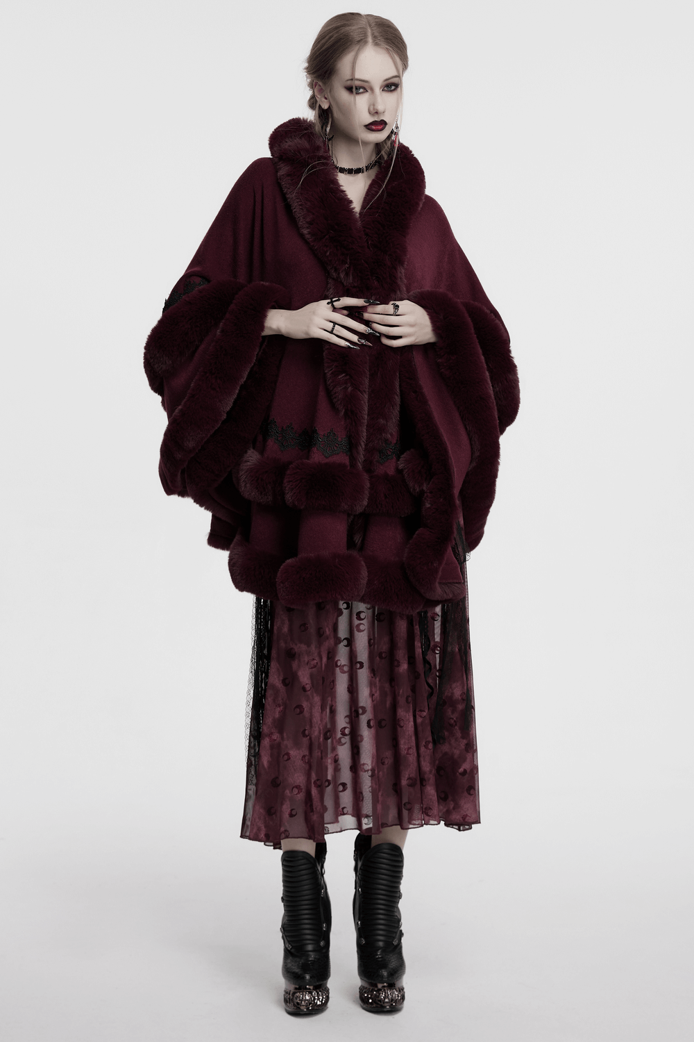 Model showcasing a burgundy hooded cloak with luxurious fur trim and intricate lace hem.