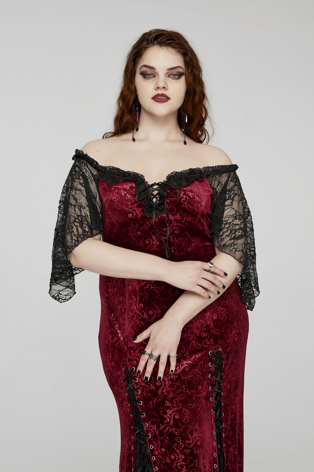 Model showcasing a burgundy off-shoulder velvet gown with lace sleeves, embodying gothic elegance and allure.