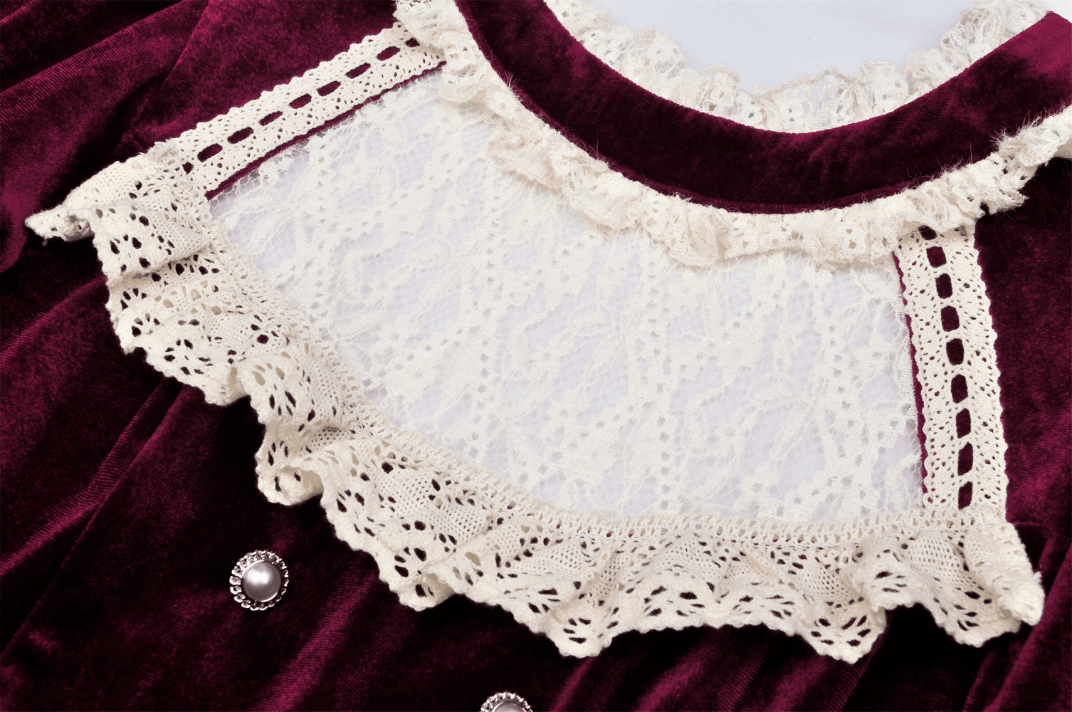 Close-up of burgundy velvet dress with intricate lace collar accents, showcasing vintage-inspired elegance.