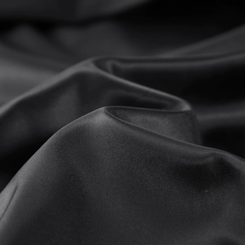 Close-up of smooth black fabric with elegant drapes, perfect for stylish clothing designs.