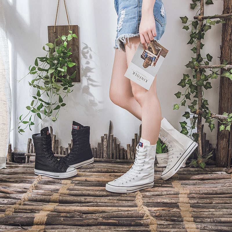 Stylish woman showing off black and white canvas lace-up mid calf sneakers in a chic room setting. Perfect for a rock look!