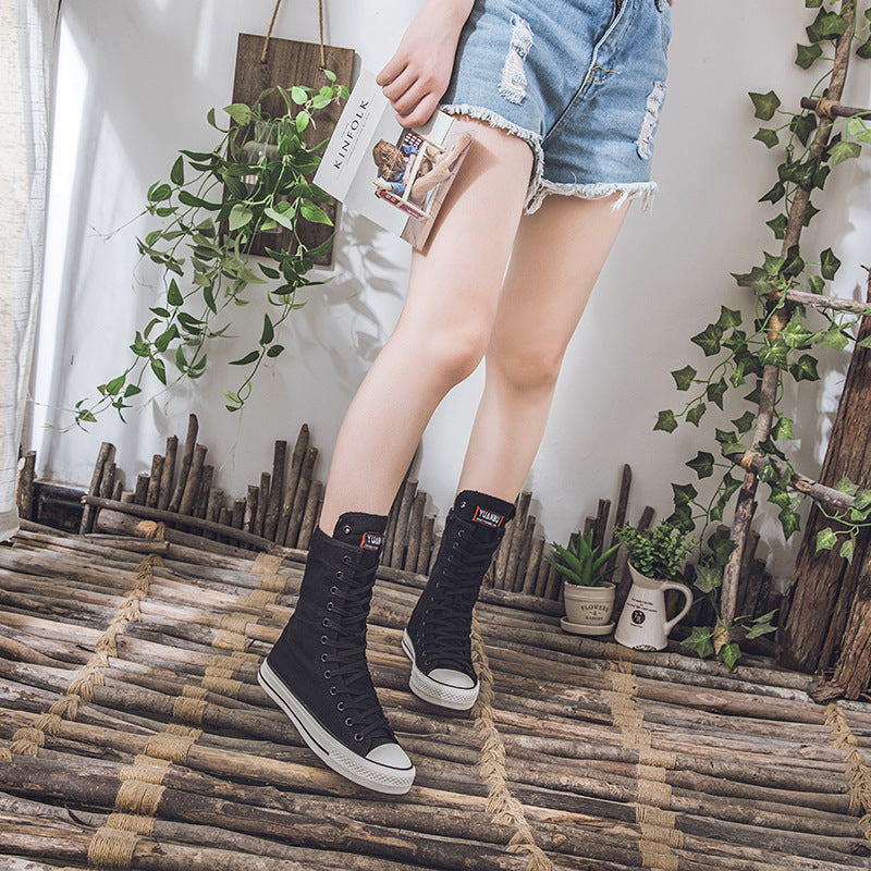 Women in black lace-up mid-calf canvass sneakers, showing off a punk look with denim shorts and a stylish vibe.