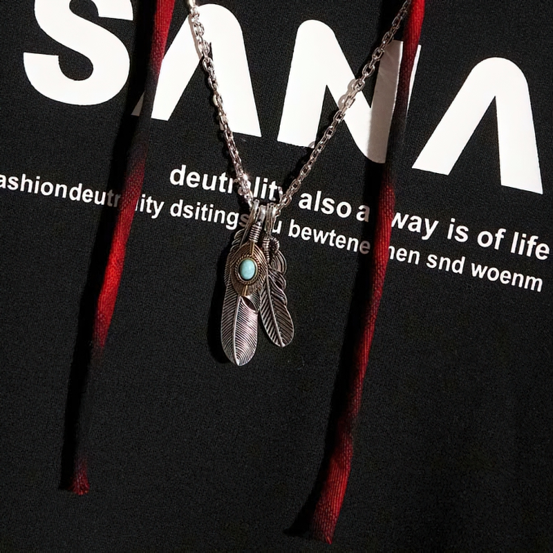 Close-up of a stylish black hoodie with a trendy letter print and a silver feather necklace.