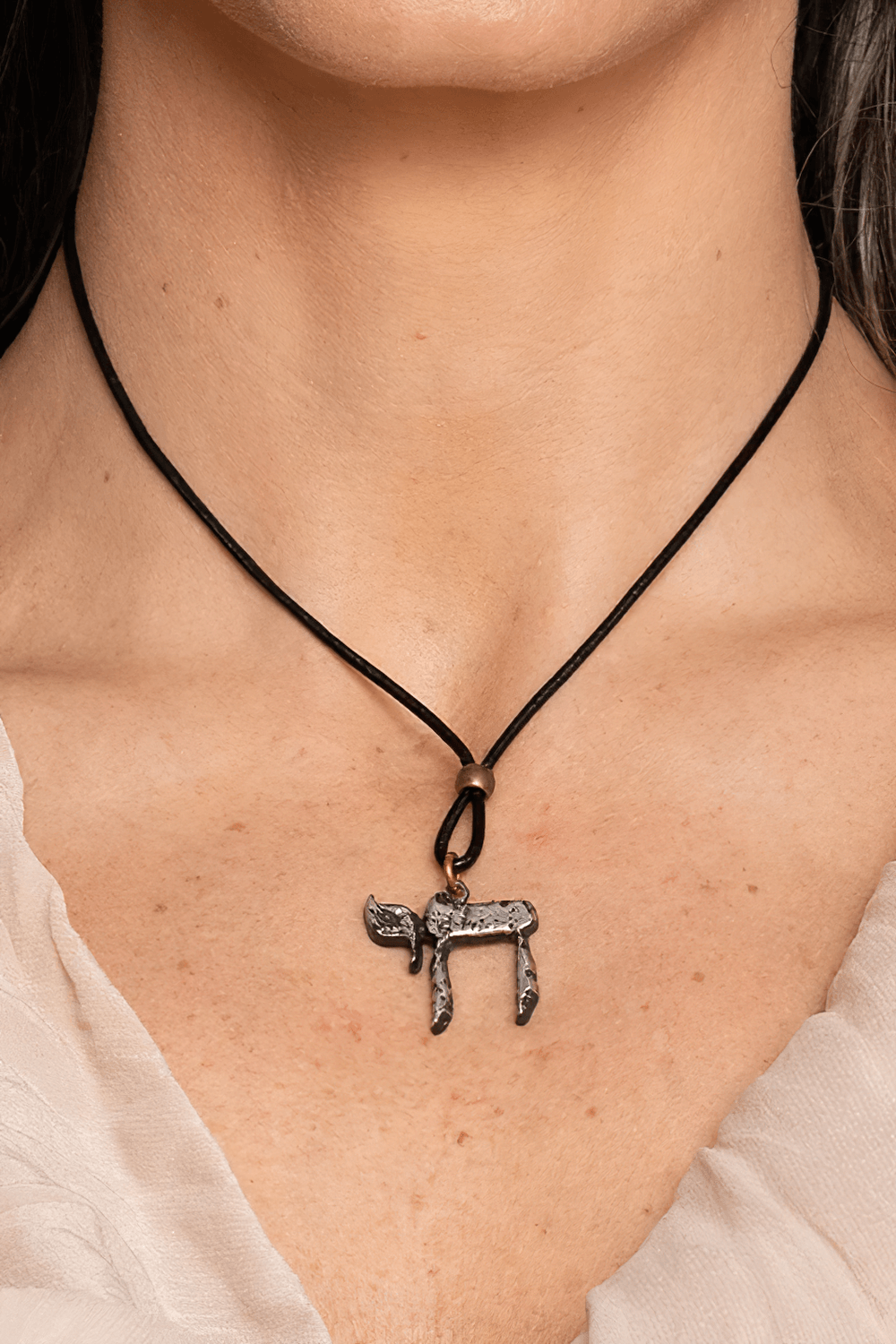 Chai Hebrew Life Symbol Pewter Pendant Necklace worn on a black cord by a model.