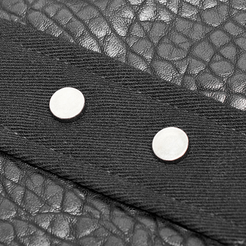 Close-up of metallic snaps on a textured black chest protector vest with adjustable lacing and zipper.