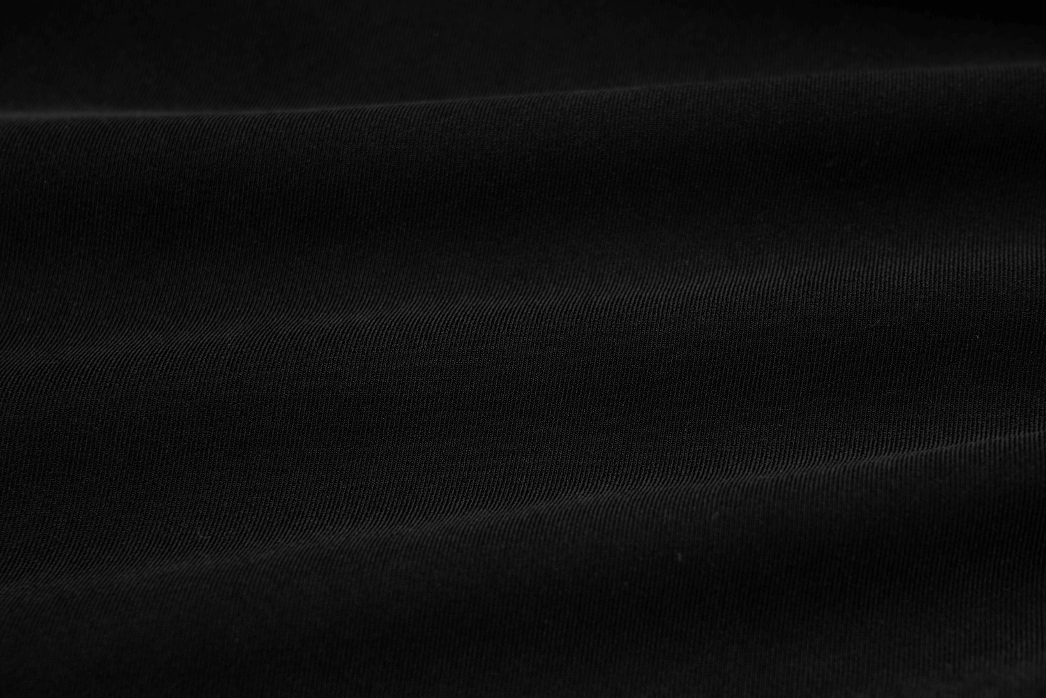 Close-up of luxurious black twill fabric, showcasing its smooth texture and high-quality finish for elegant apparel.