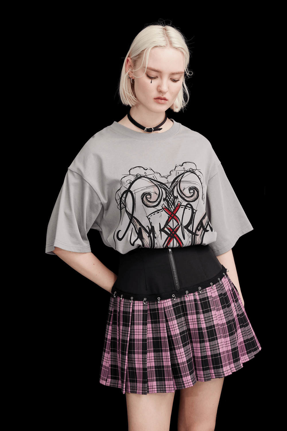 Model showcasing a chic A-line plaid skirt with metal ring accents, paired with a graphic oversized tee.
