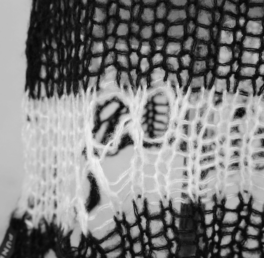 Close-up of chic black and white striped knit sweater revealing unique knitted texture and stylish holes.