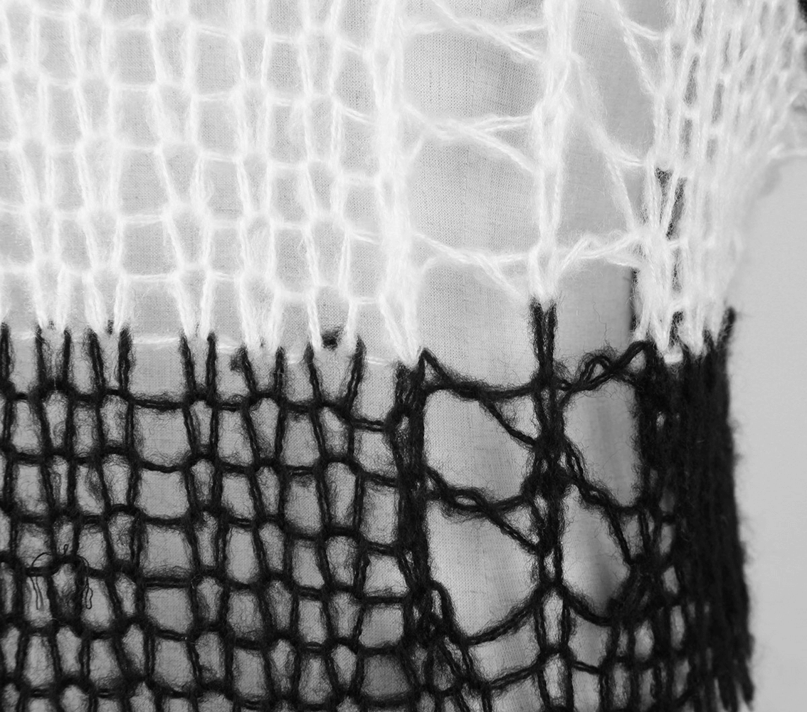 Close-up of a chic black and white striped knit pattern showcasing unique holes in a stylish long sweater.