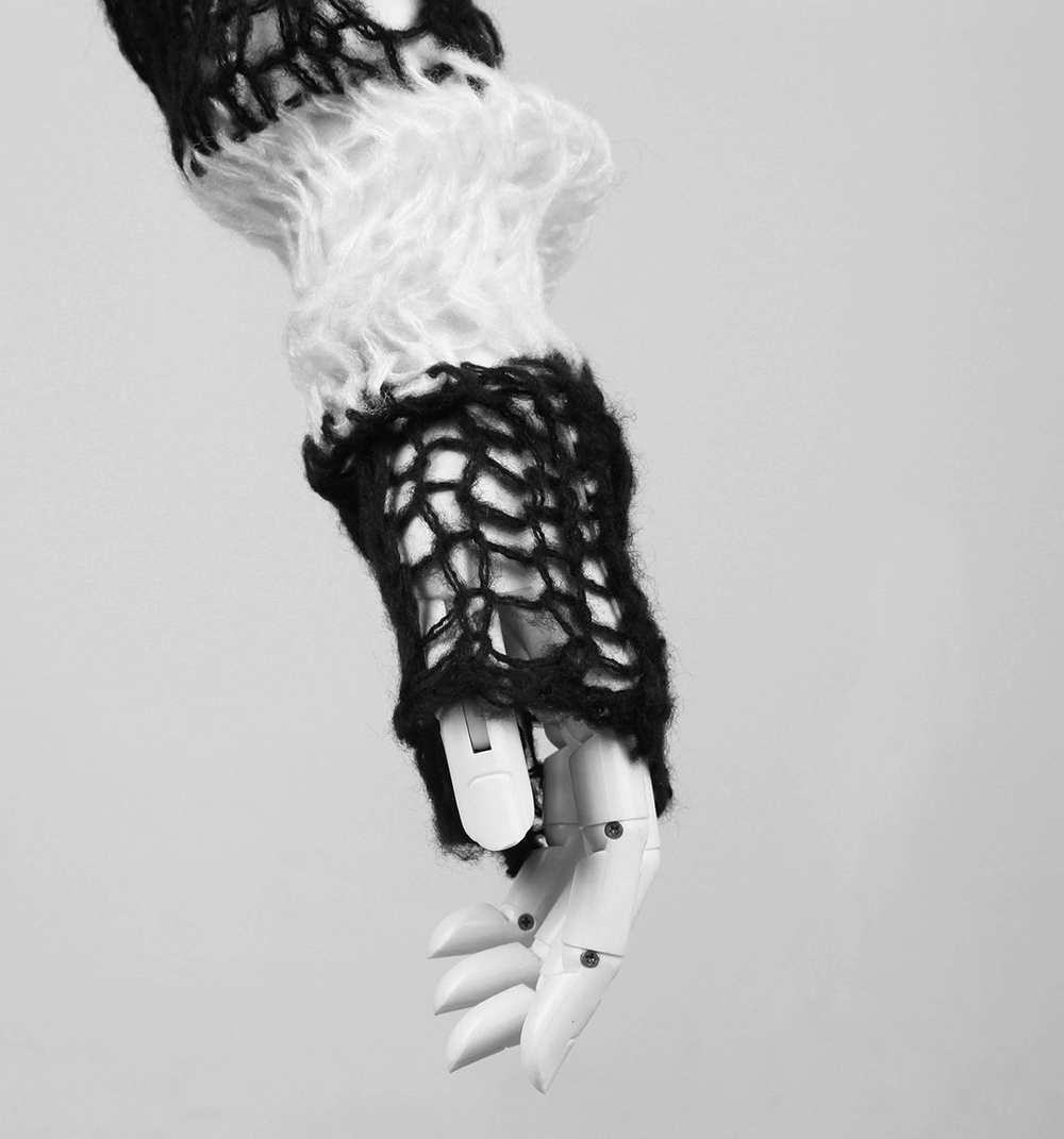 Close-up of a robotic hand showcasing a chic black and white striped sweater sleeve with unique knit patterns.