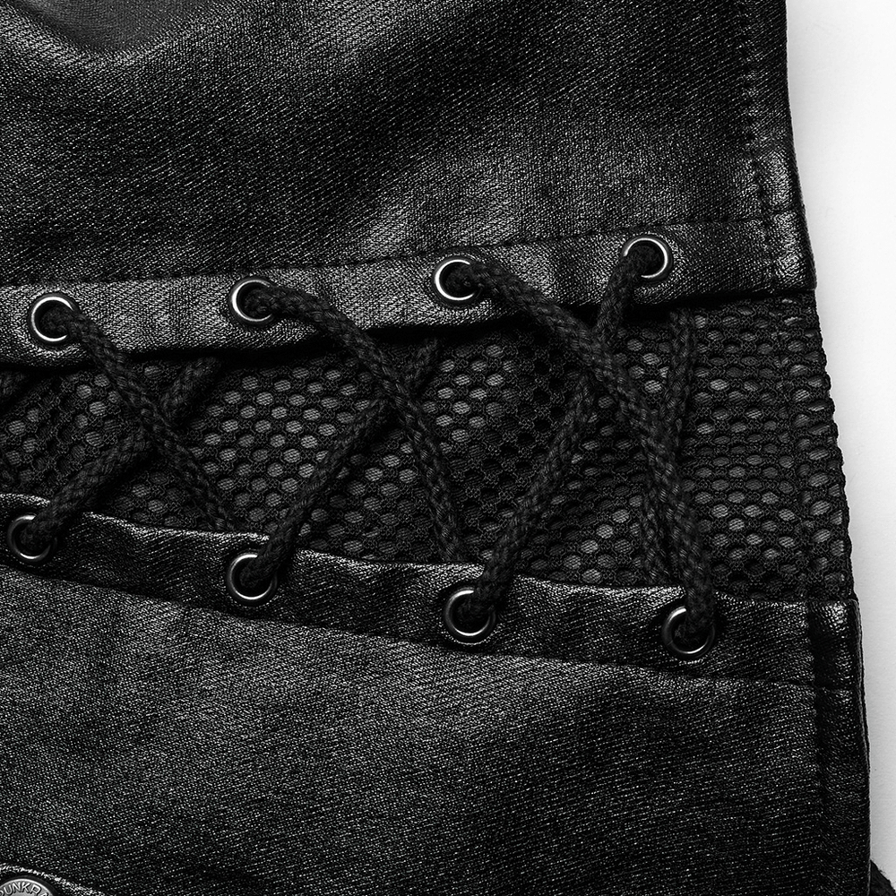 Close-up of chic black asymmetric top showcasing eyelet details and mesh fabric accents.