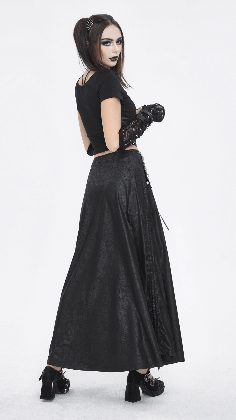 Model showcasing a chic black faux leather buckled long skirt with slit, styled in a gothic look.