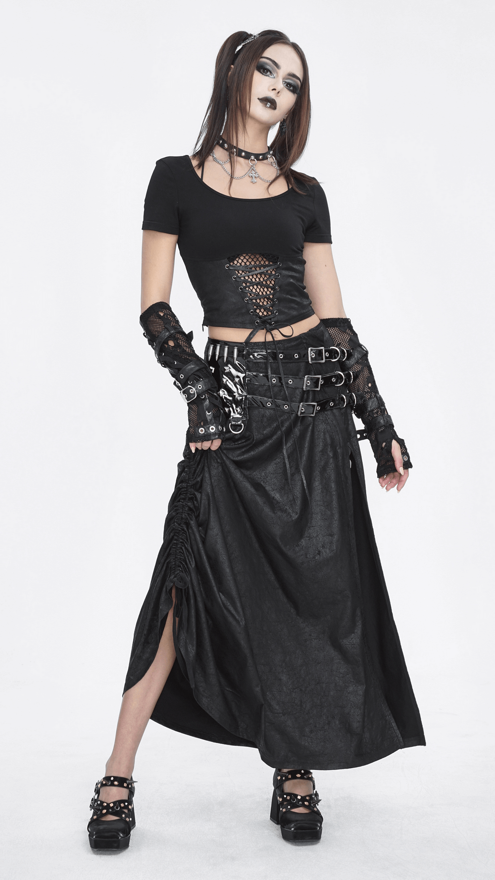 Model wearing a chic black faux leather long skirt with buckles and a cropped top for an edgy gothic look.