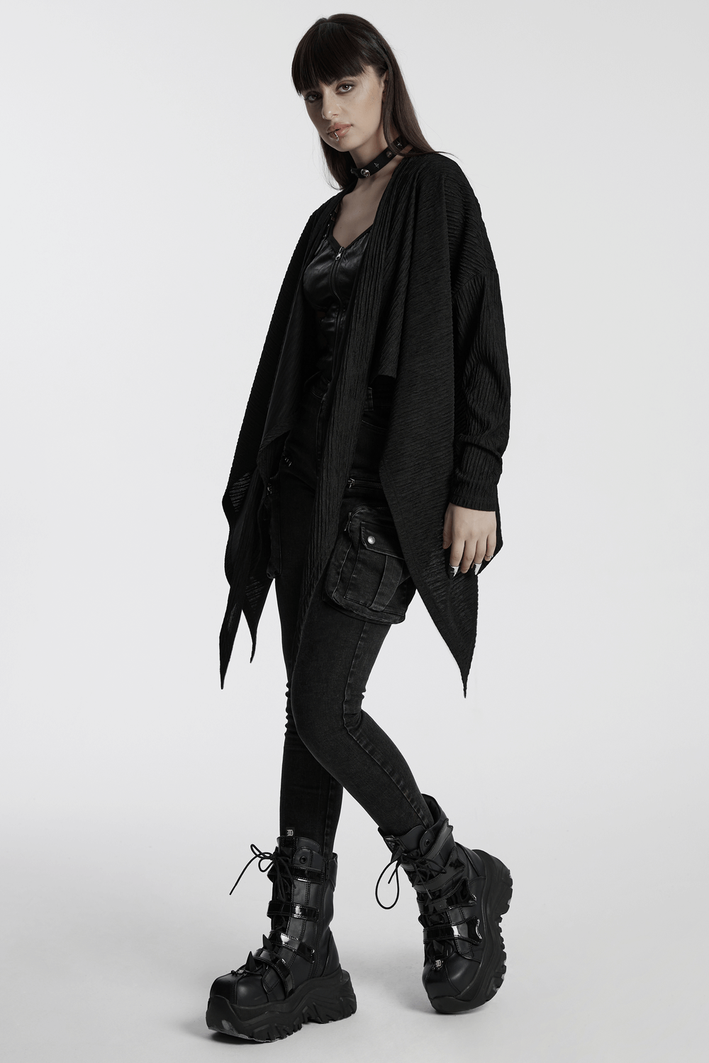 Chic black knit fashion cape for women, layered over sleek punk outfit, featuring unique irregular hem and dynamic fit.