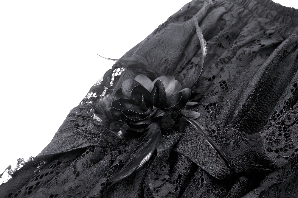 Close-up of a chic black lace asymmetrical skirt featuring intricate lace details and a decorative floral accent.