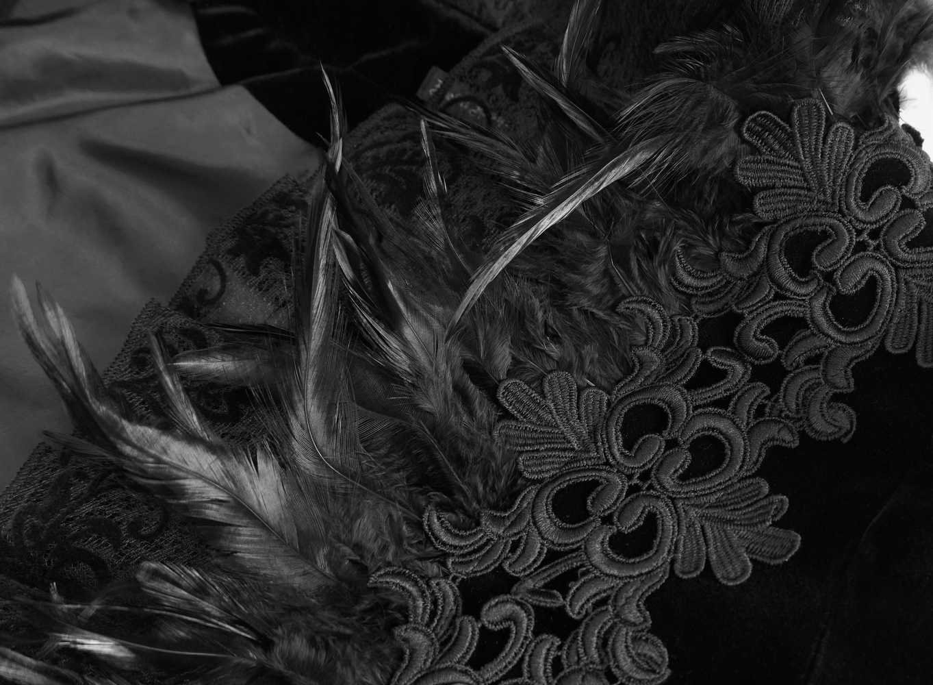 Chic black lace bolero with feathers and intricate chain accents, showcasing gothic elegance and style.