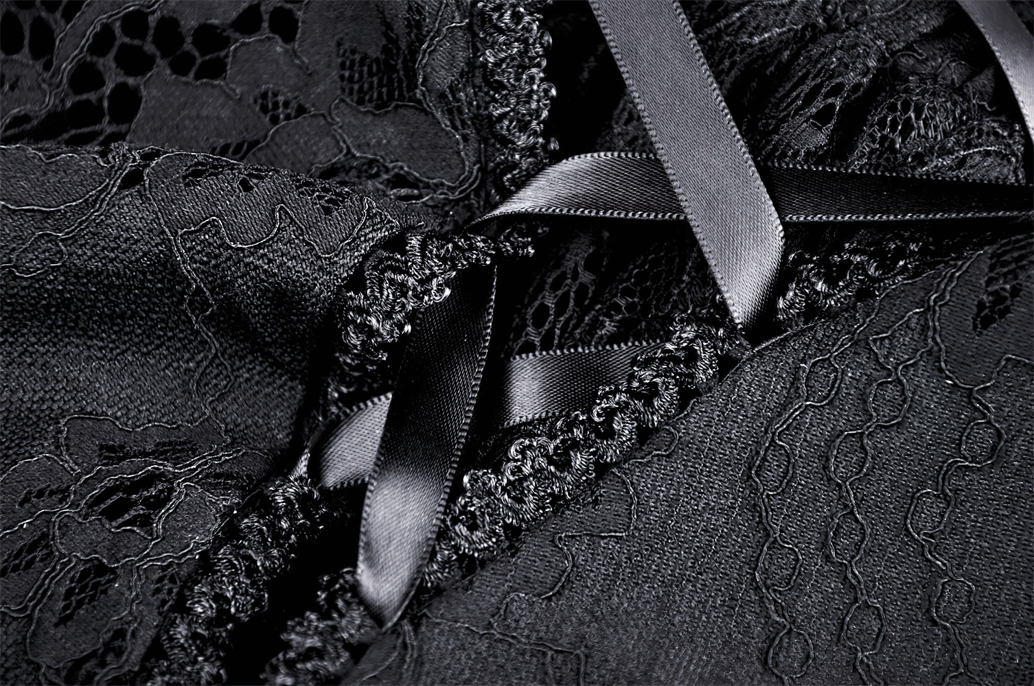 Close-up of elegant black lace fabric featuring intricate patterns and luxurious satin ribbons in a corset style.