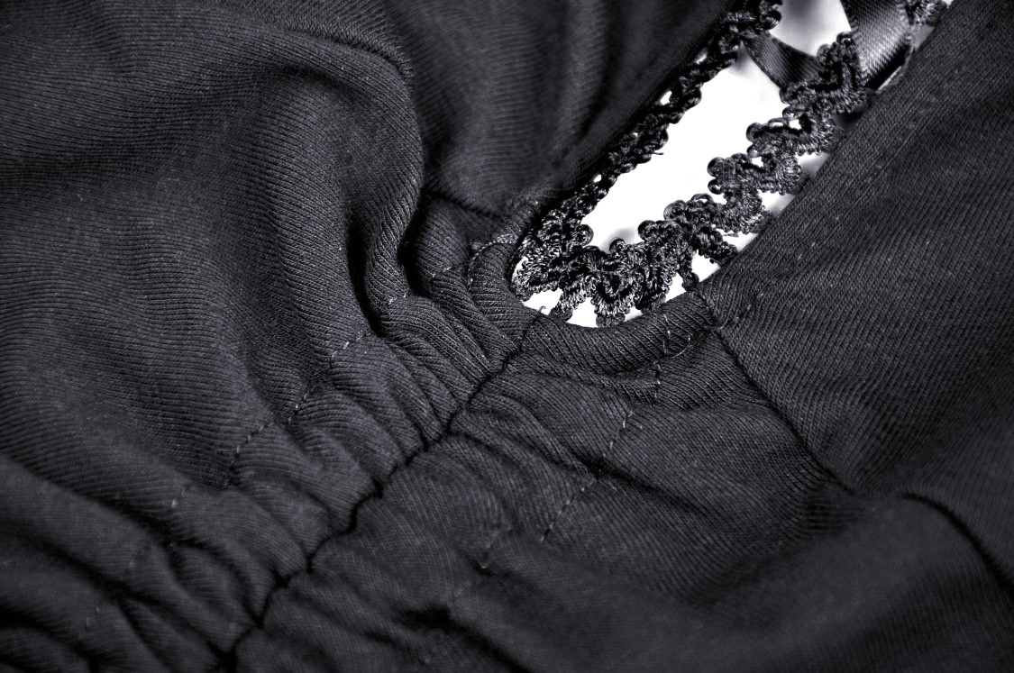 Close-up of the lace detailing and ruched fabric on a chic black lace-up mini dress.