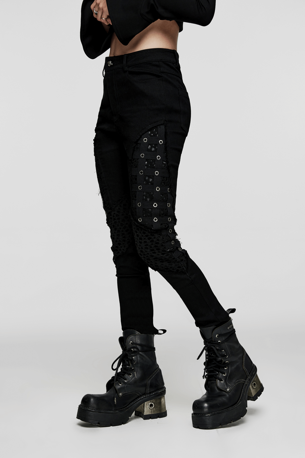 Chic black rubberized mesh punk cage pants with geometric eyelets, styled with combat boots for a gothic look.