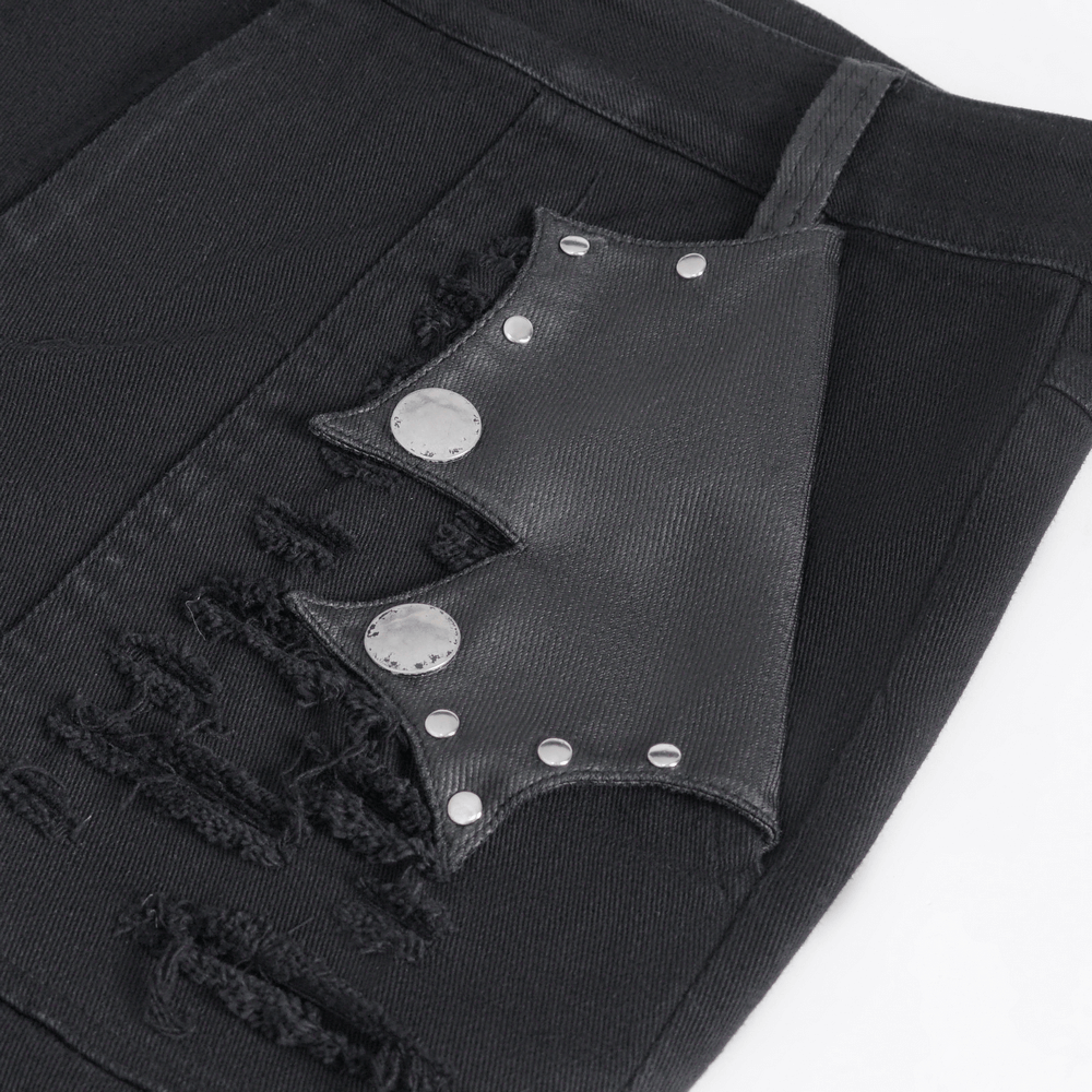Close-up of chic black studded ripped jeans featuring buckle details and distressed fabric.