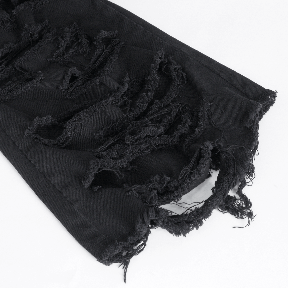 Close-up of distressed black jeans with frayed edges, showcasing trendy ripped details.