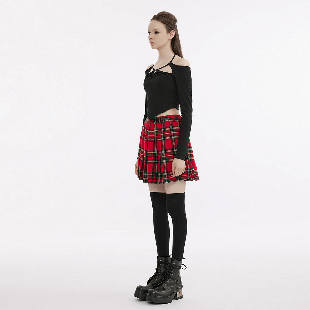 Model wearing a black off-the-shoulder top with plaid skirt and knee-high socks, showcasing a chic, playful goth style.