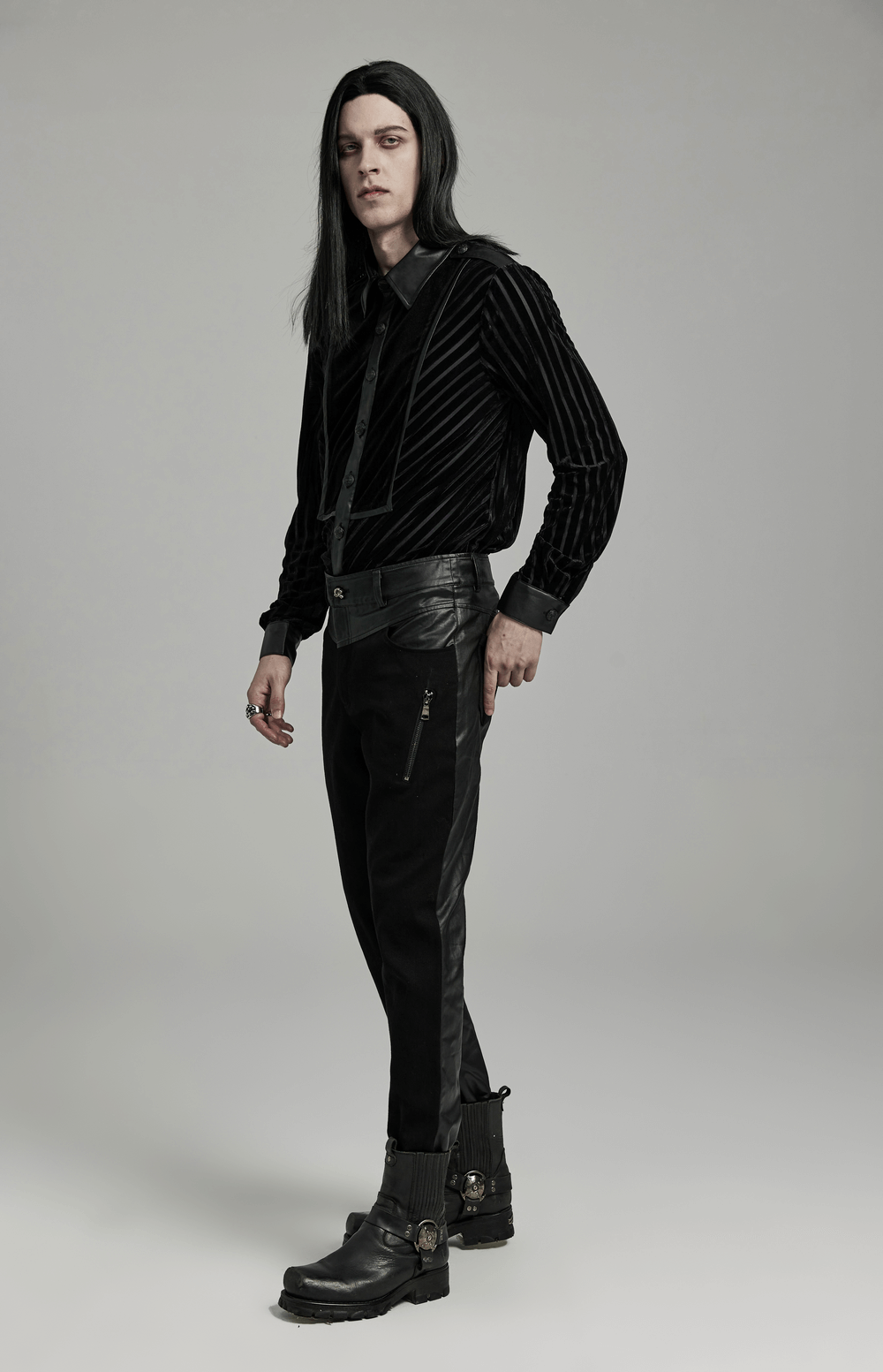 Stylish man in chic black tactical striped velvet shirt and sleek black pants, exuding modern elegance.