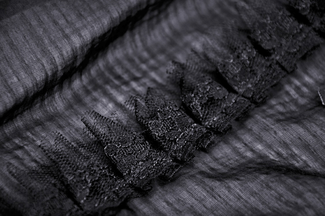 Close-up of black gothic lace fabric with ruffled details, perfect for a chic Victorian-style top.