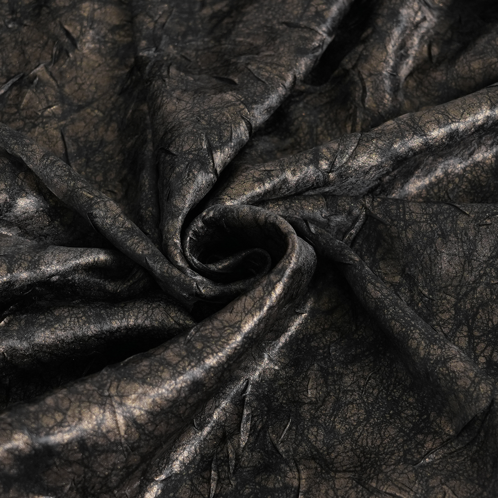 Close-up of dark, textured fabric with a crinkled faux leather finish, perfect for punk rock style clothing.