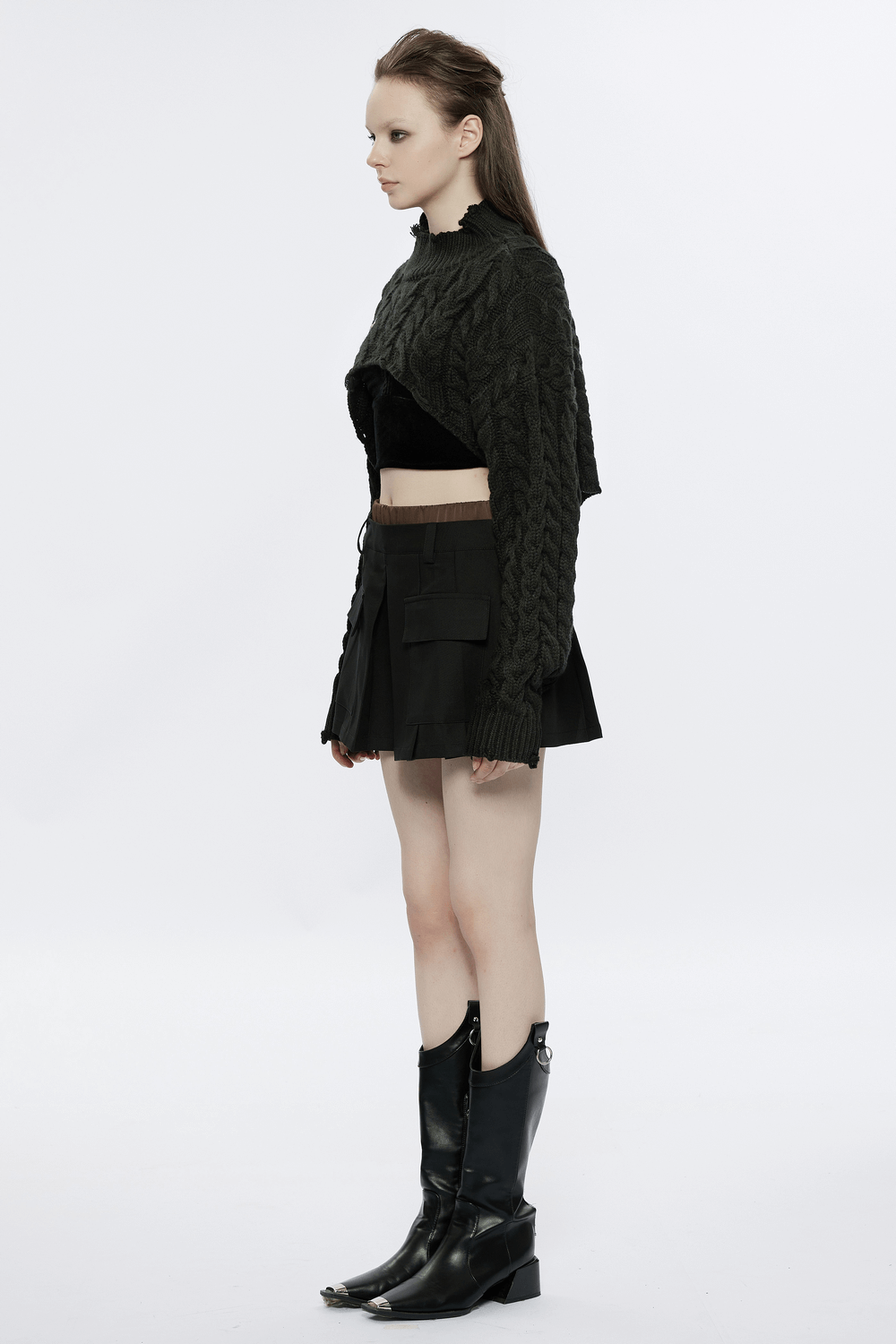 Side view of a woman in a chic cropped knit turtleneck sweater paired with a black mini skirt and stylish boots.