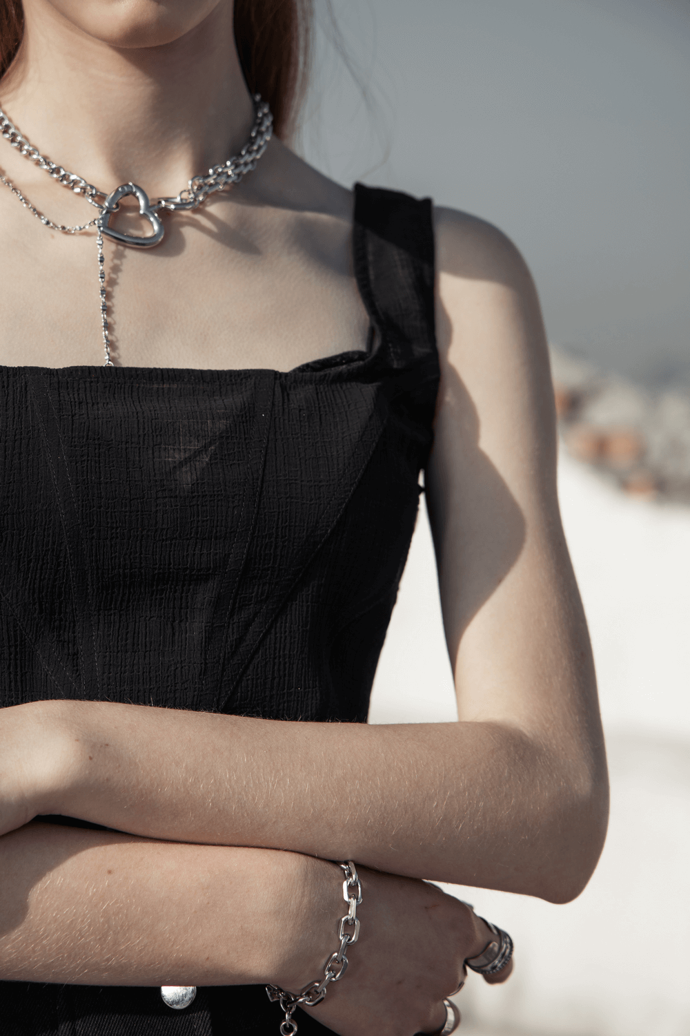 Stylish model in a chic black mesh top with square collar and layered silver accessories.