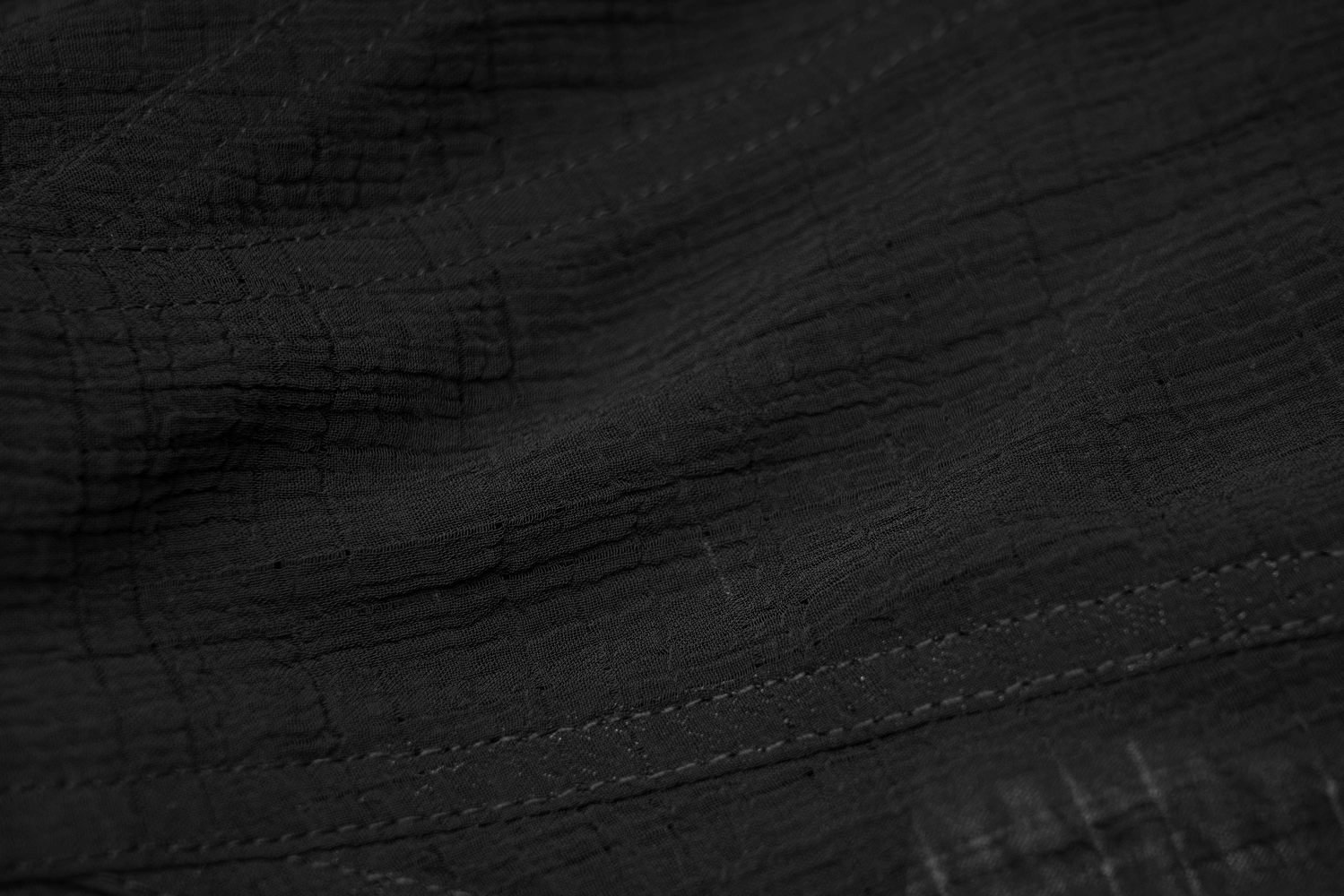 Close-up of dark woven mesh fabric showcasing textured detail and stitching for chic top design.