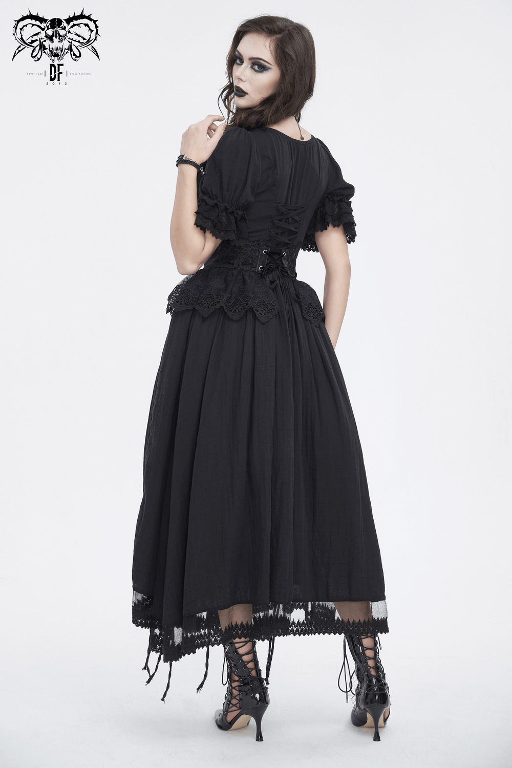 Back view of a model in a black vintage-inspired dress with lace details and corset features.