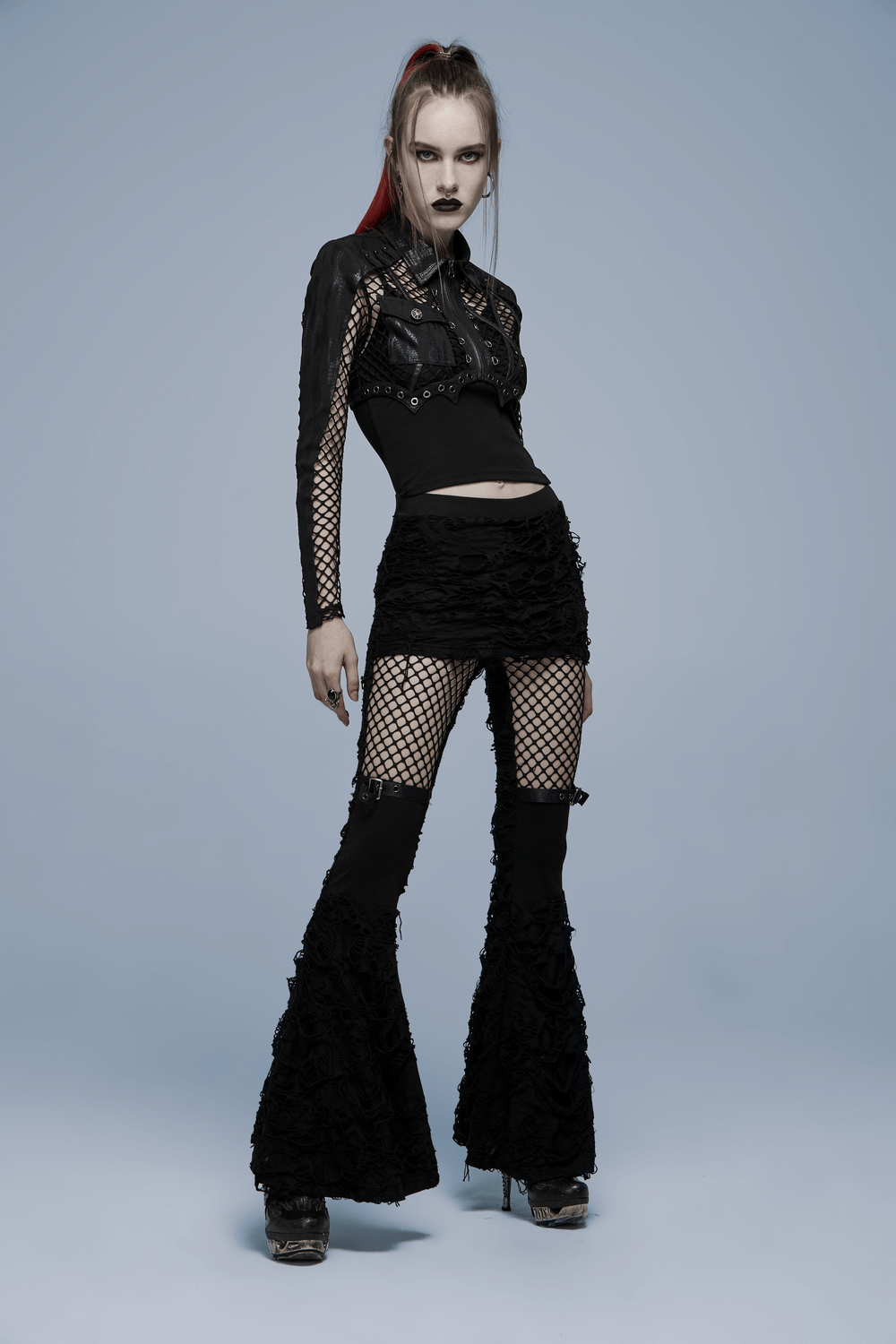 Chic Gothic punk model in a fishnet crop top and flared pants, showcasing edgy mesh and faux leather accents.