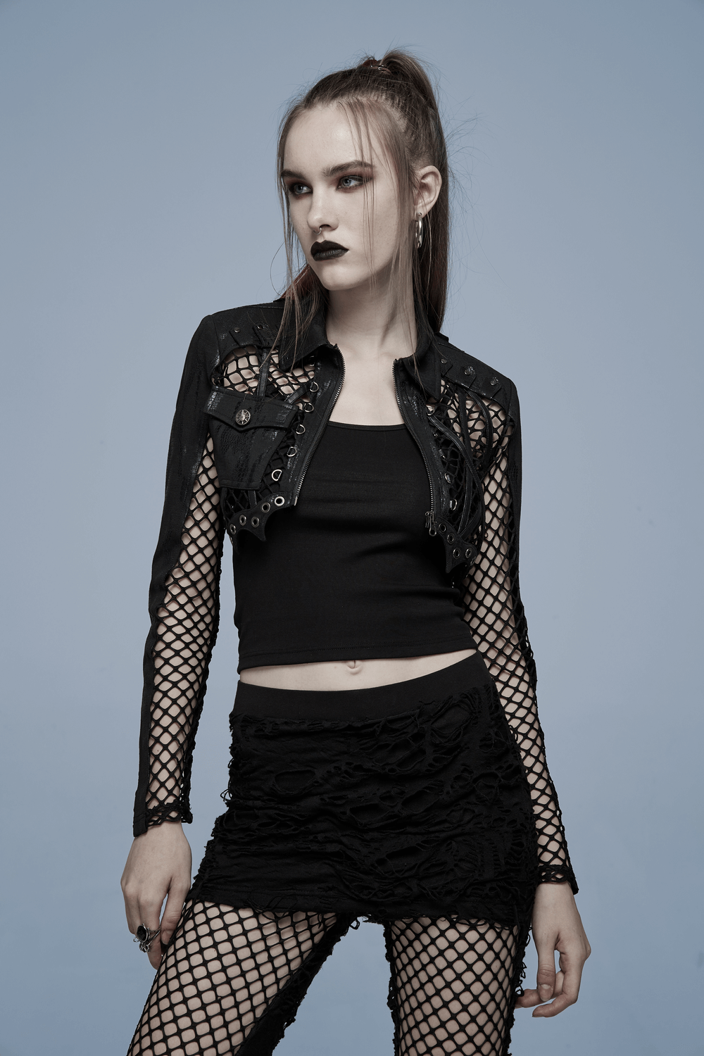 Model wearing a chic fishnet sleeved crop top with gothic leather accents and punk-inspired look.