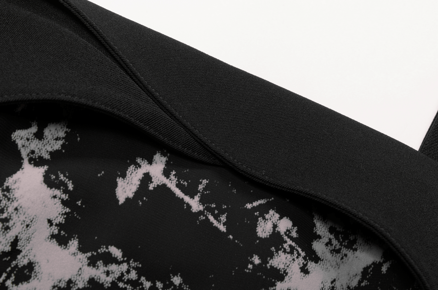 Close-up of the chic black and white abstract fabric of the A-line mini dress featuring a smooth neckline and stylish pattern.