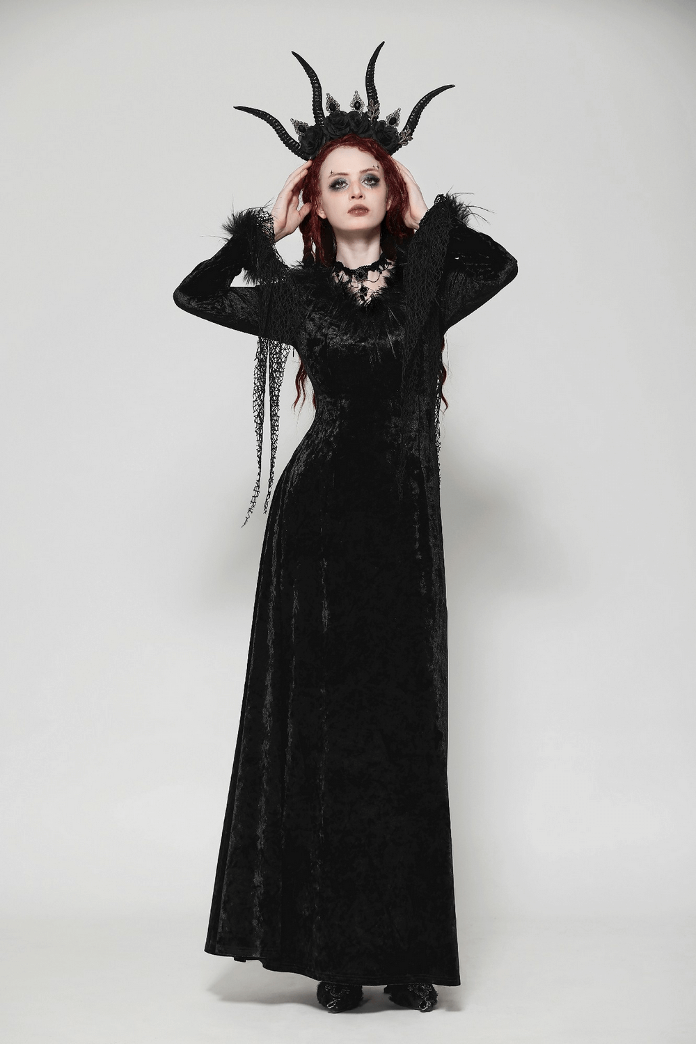 Elegant goth model in a black velvet maxi dress with lace accents and dramatic crown, showcasing dark sophistication.