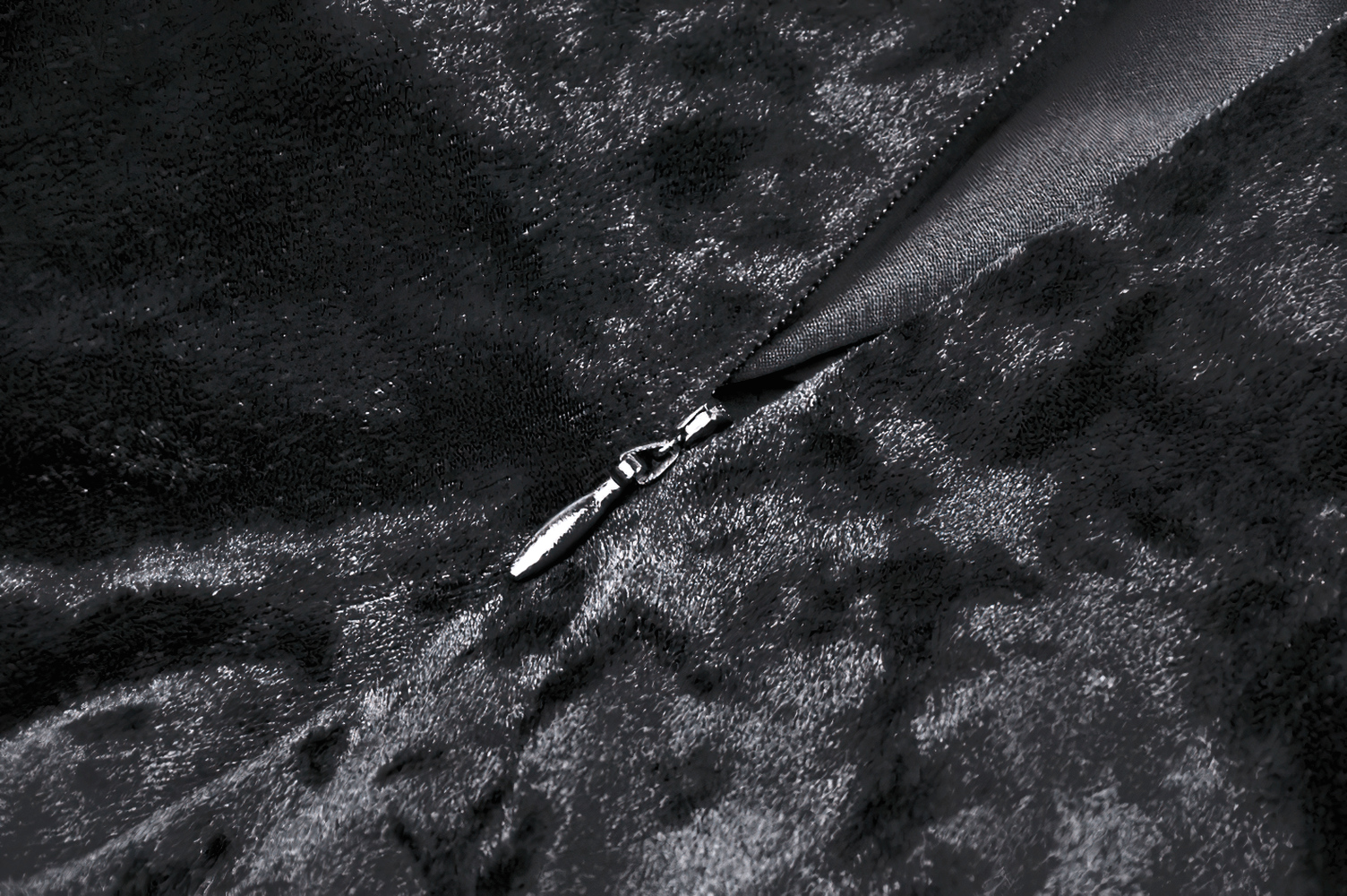 Close-up of a sleek black velvet fabric with a shiny zipper, showcasing luxurious texture and goth elegance.