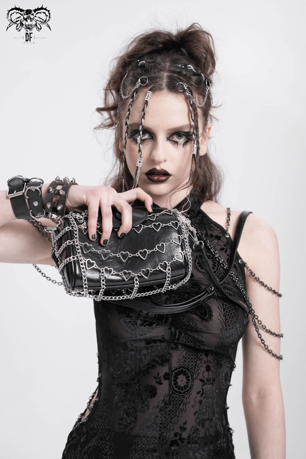 Trendy black heart pattern chain crossbody bag showcased by a model in edgy fashion attire.